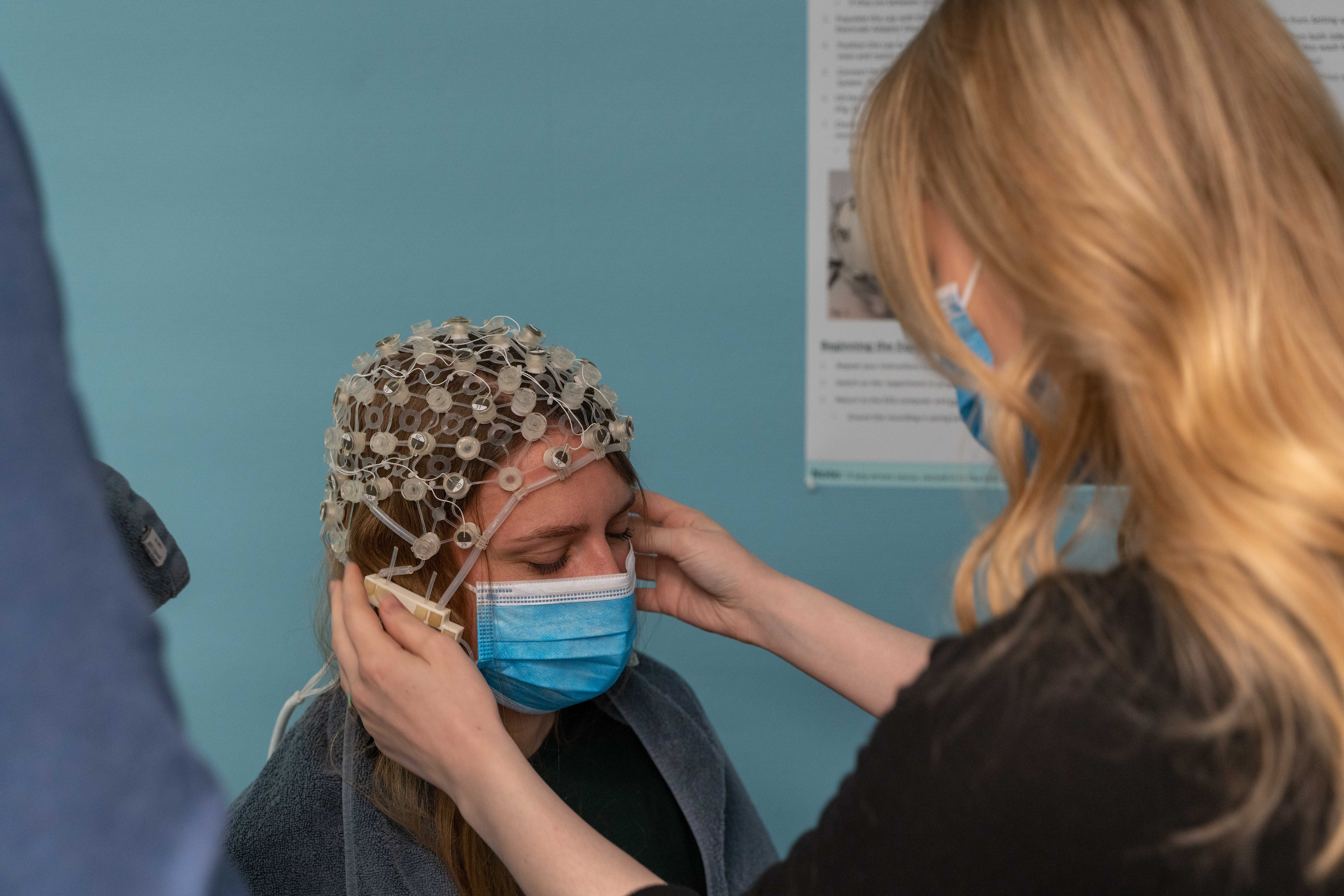 Masterstudent Hilde Kristin Øien Thomsen justerer en EEG-cap med elektroder på hodet til en deltaker. Foto: Christian Halvorsen
